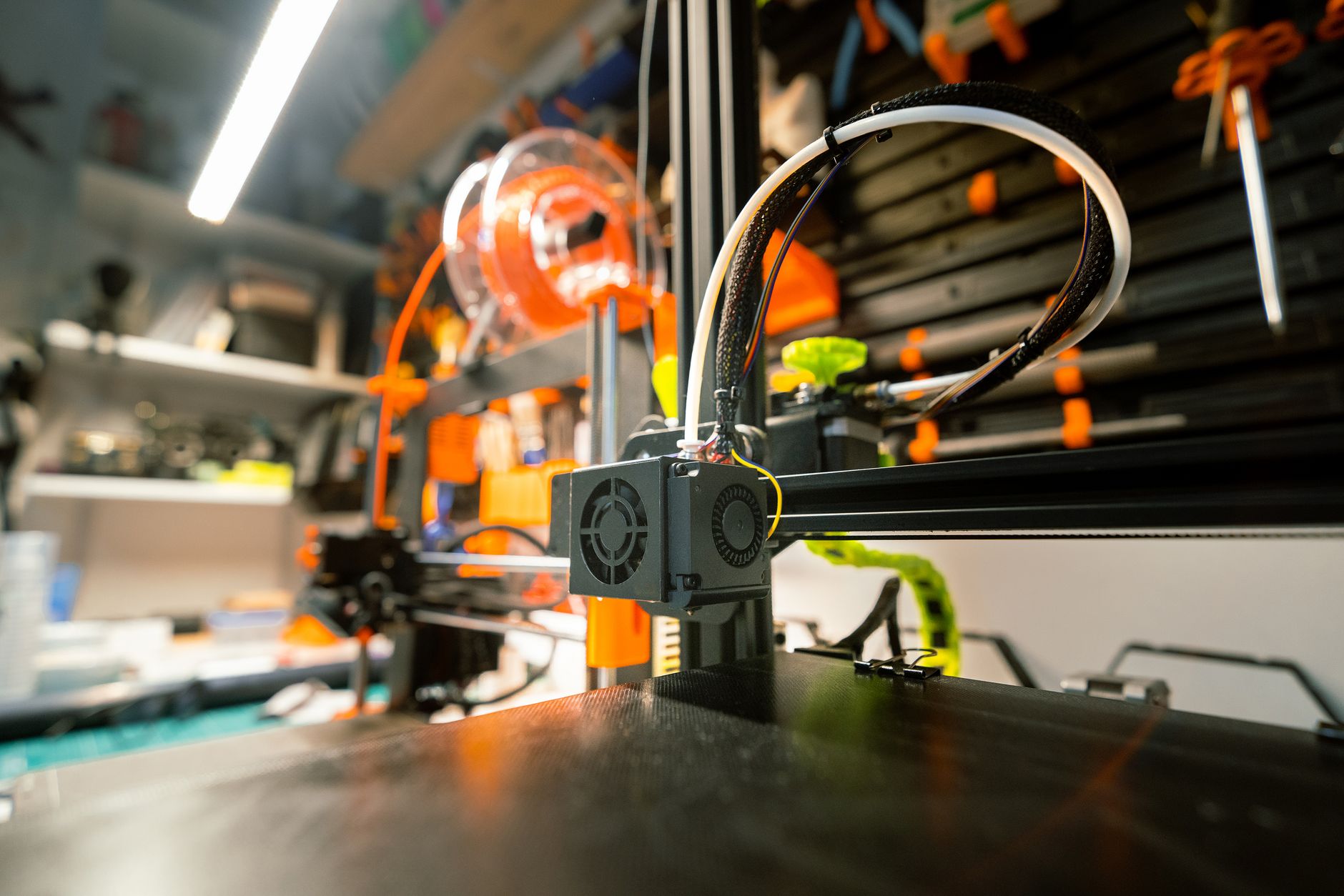Compact Bambu Lab style 3D printer printing a red benchy on a desk