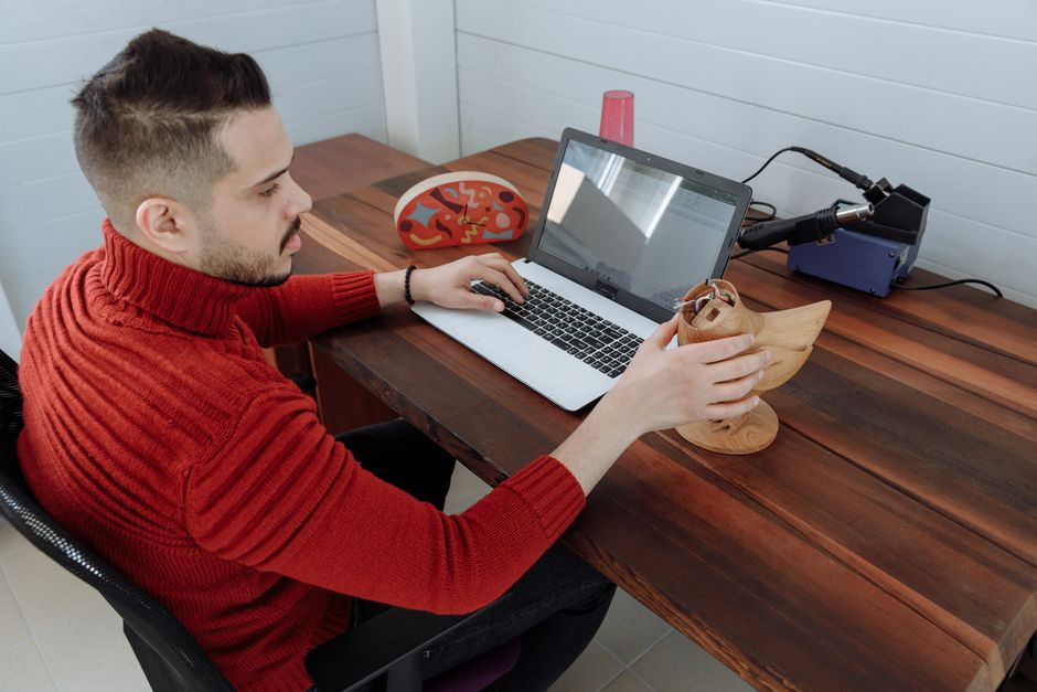 A modern desktop FDM 3D printer on a clean desk next to a laptop